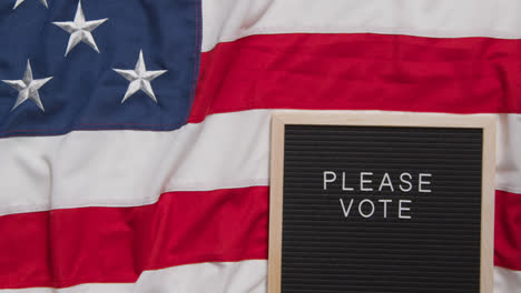 Schild-Mit-Der-Aufschrift-„Bitte-Stimmen-Sie-Ab“-Liegt-Auf-Der-US-Flagge-„Stars-And-Stripes“-Für-Die-Amerikanische-Wahl-2024-1
